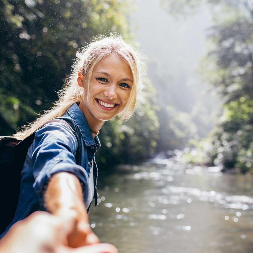 Blonde woman in river stretches out hand